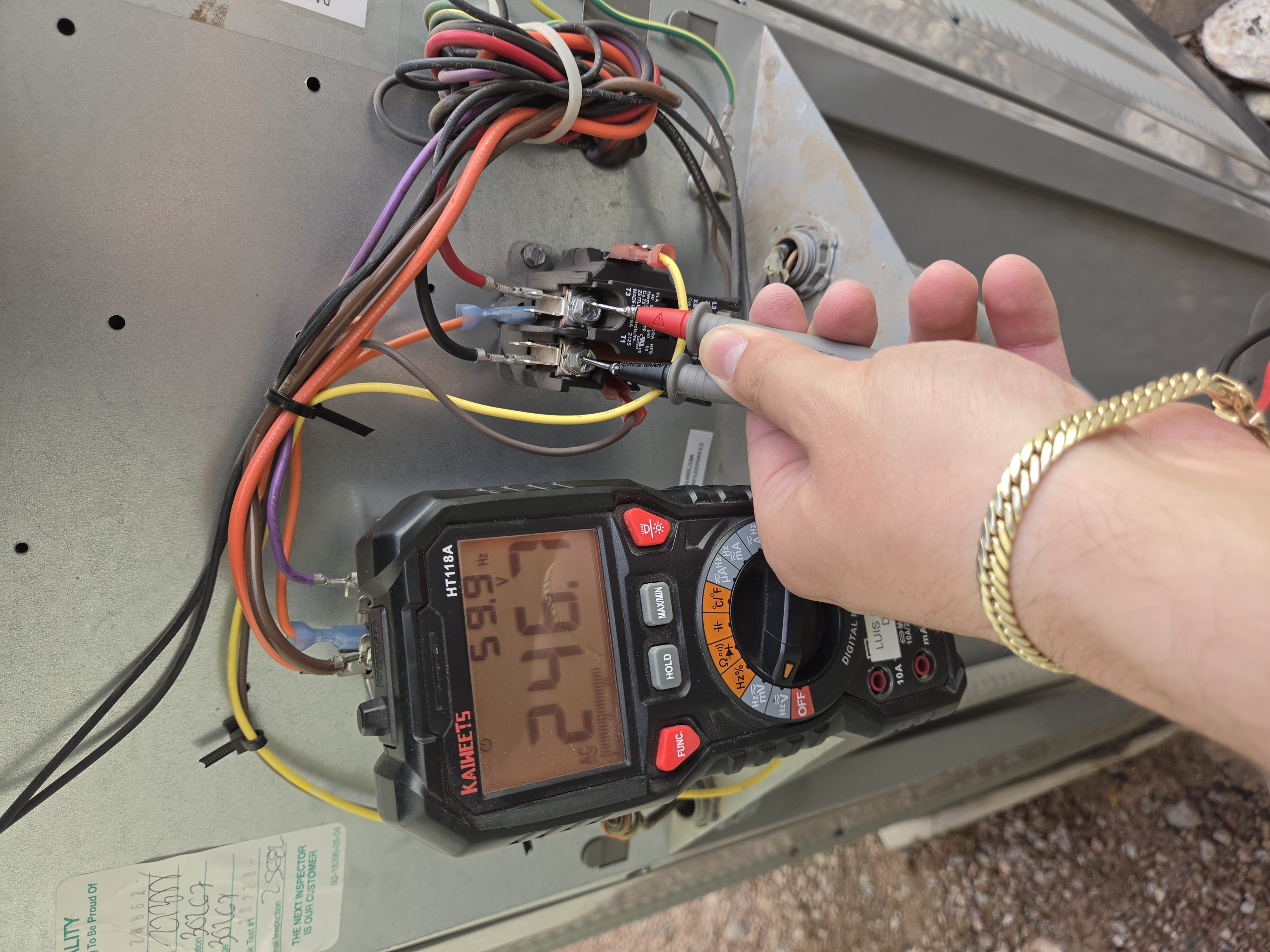Digital multimeter checking AC load voltage at contactor during service